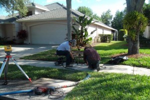 A contractor repairing a sidewalk in a suburban neighborhood