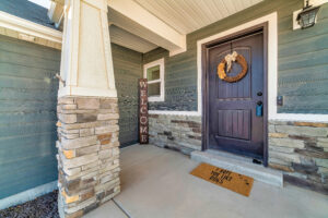 Open porch at home facade with stone wall wood siding and wreath on front door